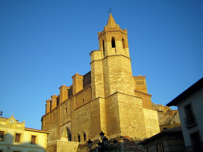 Majestic ancient church at sunset, showcasing intricate brickwork and tall towers against a clear blue sky.