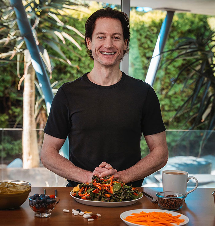Billionaire in a casual setting, smiling with a healthy meal, coffee, and supplements, symbolizing efforts to reverse aging. Billionaire in a casual setting, smiling with a healthy meal, coffee, and supplements, symbolizing efforts to reverse aging.