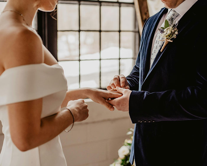 Bride and groom exchanging rings in a ceremony, highlighting an influencer's wedding scam. Bride and groom exchanging rings in a ceremony, highlighting an influencer's wedding scam.