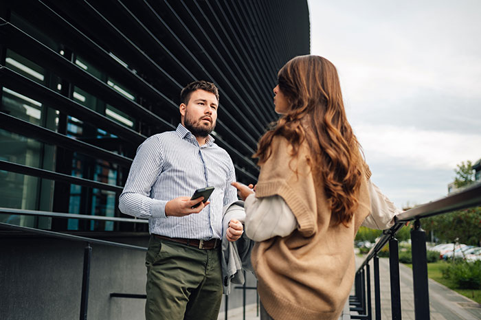 Two people standing outside a modern building, discussing an apartment scam incident. Two people standing outside a modern building, discussing an apartment scam incident.