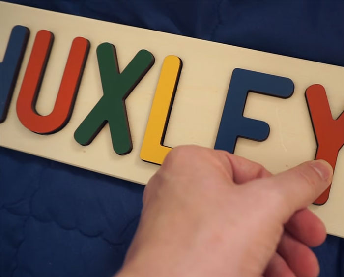 Puzzle spelling "Huxley" with a hand, related to YouTubers rehoming adopted son. Puzzle spelling "Huxley" with a hand, related to YouTubers rehoming adopted son.