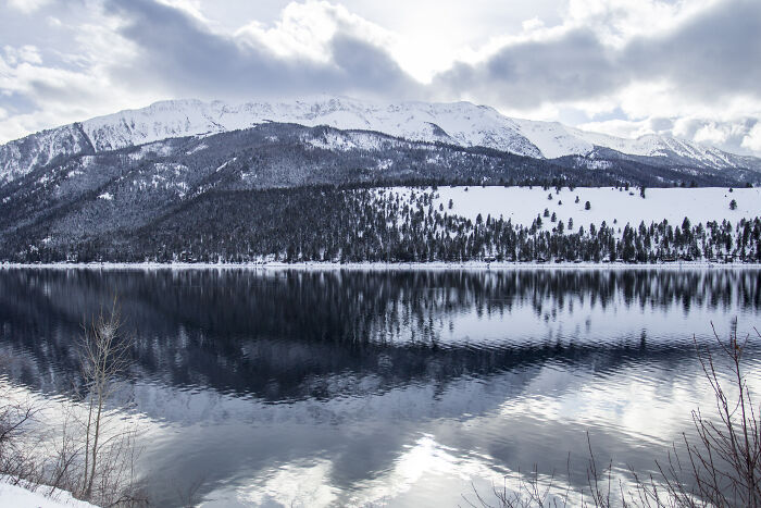 Scenic view of snow-covered mountains reflected in a calm lake, showcasing amazing views in winter.