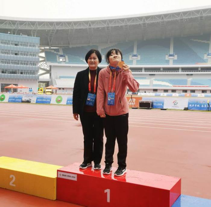 Social media star proudly holds a medal on the winner's podium at a stadium event. Social media star proudly holds a medal on the winner's podium at a stadium event.
