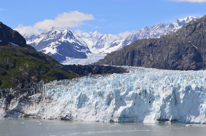 Amazing views of icy glacier surrounded by rugged mountains under a clear blue sky.
