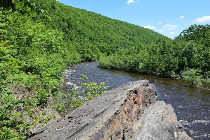 River winding through lush green mountains under a blue sky, showcasing amazing views.