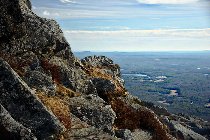 Rocky cliff with an expansive view of forests and sky, highlighting amazing views in US states.