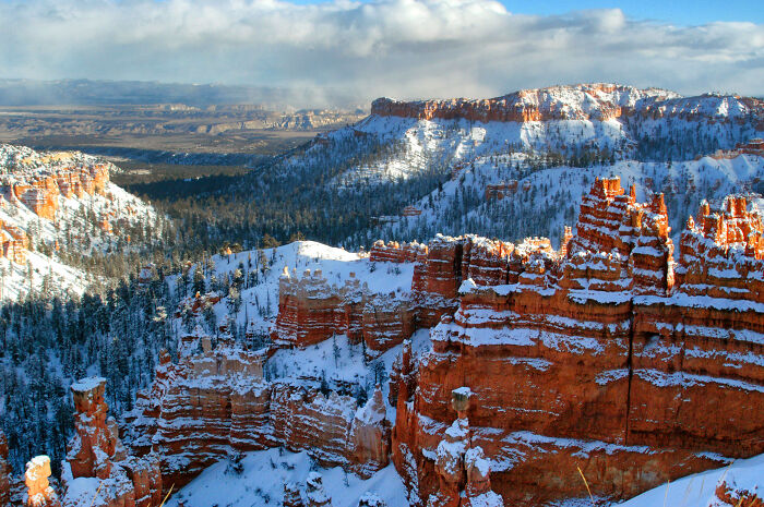 Snow-covered canyons and rock formations under a vast sky, showcasing amazing views and natural beauty.