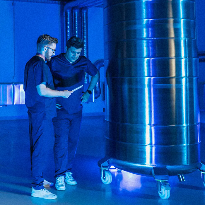 Two people in a lab, examining a large tank, related to body freezing and revival services. Two people in a lab, examining a large tank, related to body freezing and revival services.