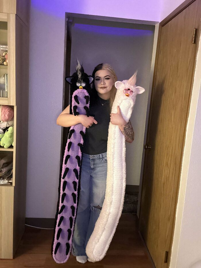 Person proudly holding two long crochet plush toys, showcasing creative crochet projects by crochet enthusiasts.