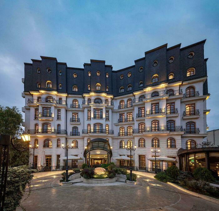 Elegant multi-story building showcasing impressive architectural feats with illuminated windows and detailed exterior design at dusk.