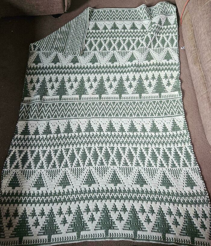 Crochet enthusiasts’ project showing a blanket with green and white patterns featuring rows of Christmas trees.
