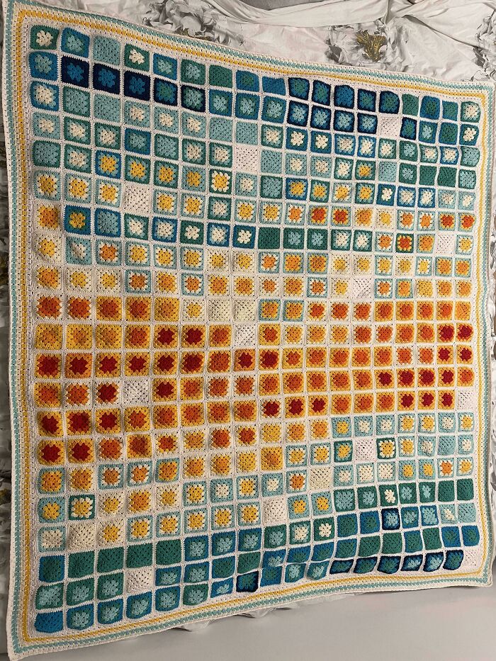 Colorful crochet blanket made of small granny squares in a gradient pattern, showcasing proud crochet project craftsmanship.