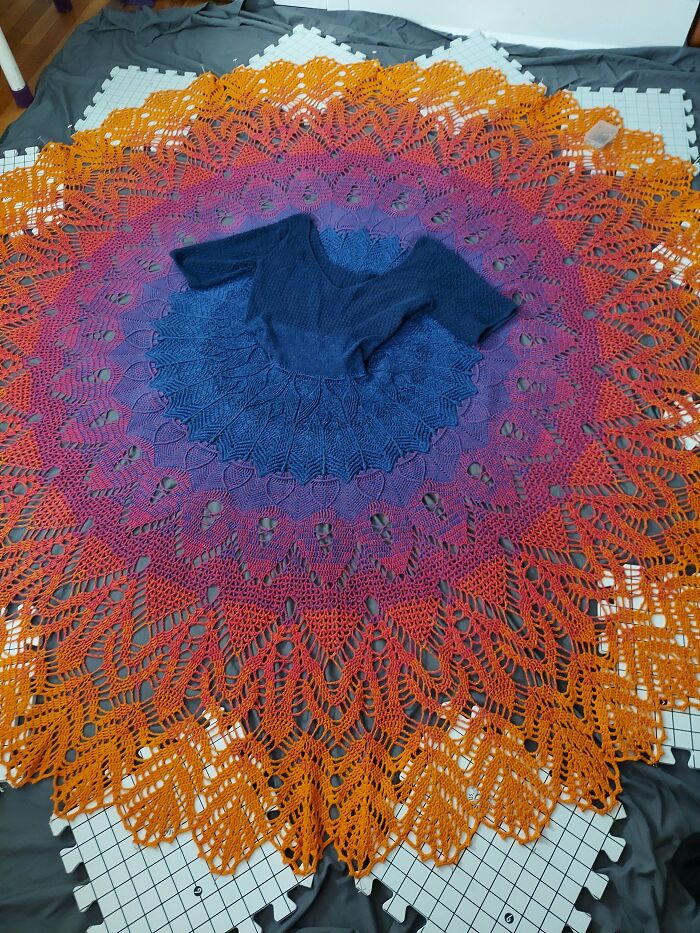 Large round crochet project with vibrant gradient colors from orange to purple, showcasing intricate patterns by crochet enthusiasts.