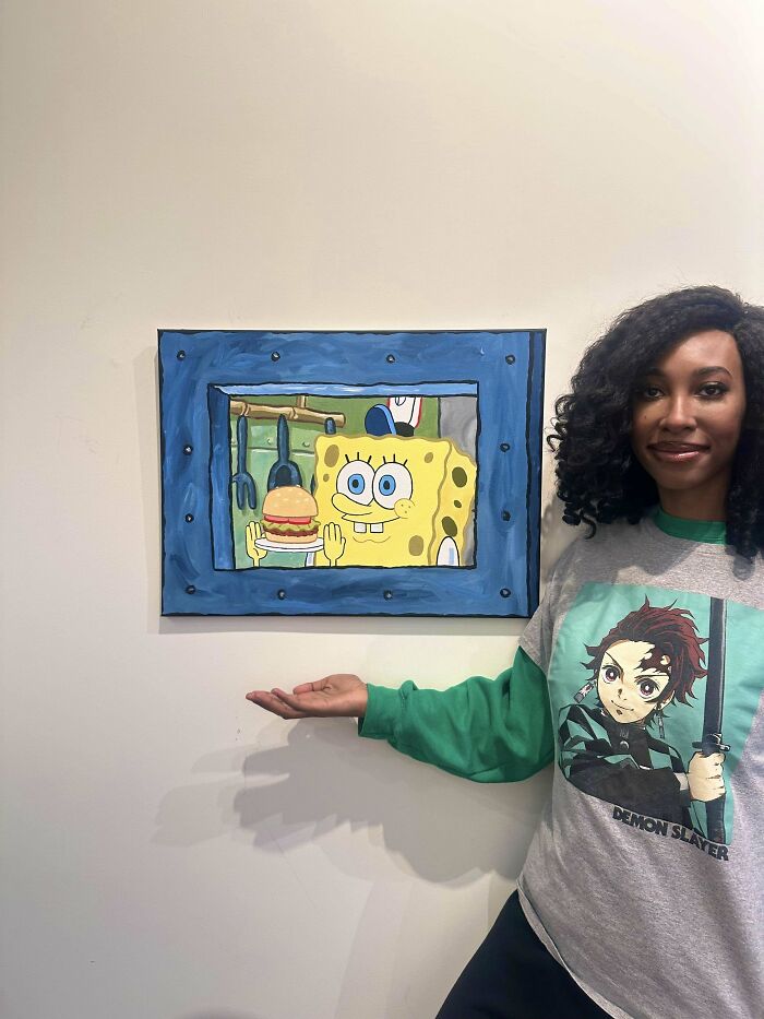 Woman showcasing a DIY SpongeBob painting on a wall.