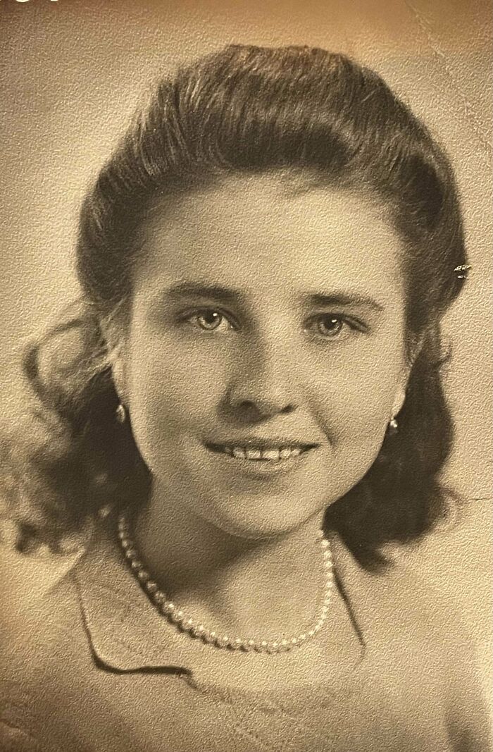 Portrait of a smiling woman with pearl necklace, taken in a historical setting.