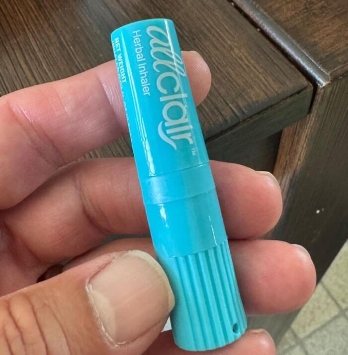 Hand holding a blue herbal inhaler, ideal for travel convenience.