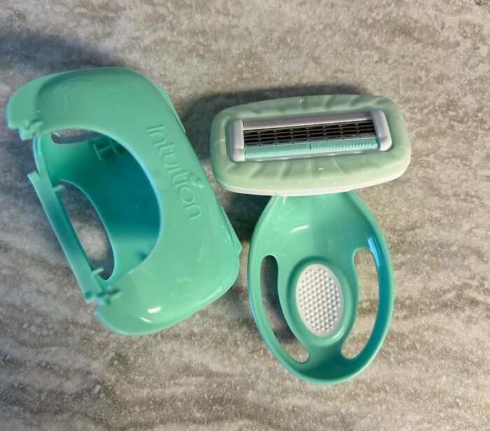 Travel essentials: mint green razor with protective cover on a textured surface.