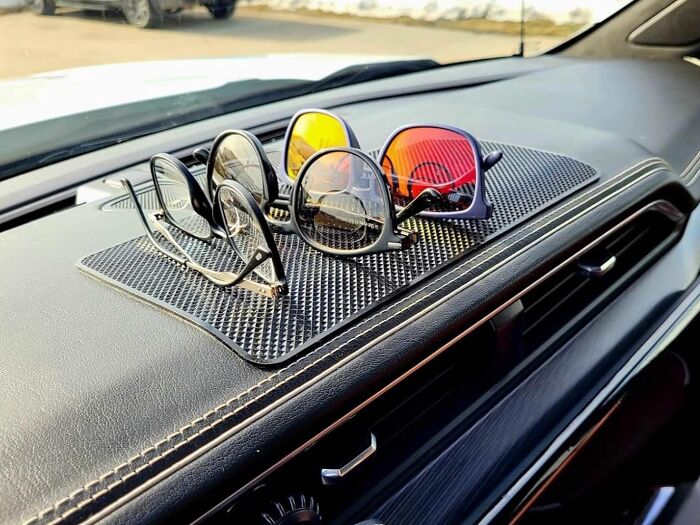 Sunglasses neatly organized on a car dashboard mat, showcasing a hack for easy everyday storage.