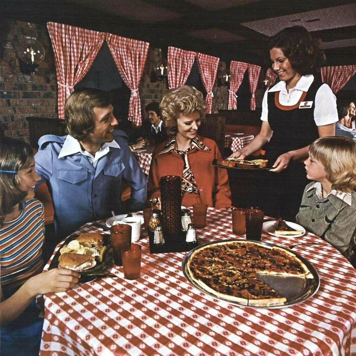 Family dining in a retro restaurant, served by a waitress.