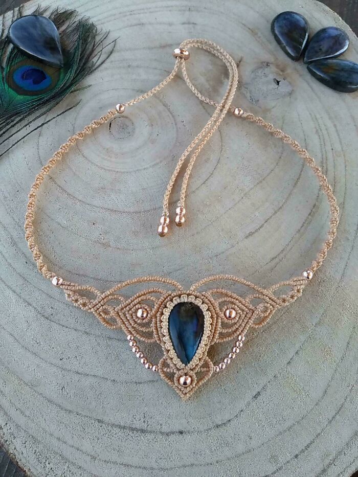 Handcrafted necklace with intricate design on wood, featuring a central dark gemstone, exemplifying amazing DIY projects.