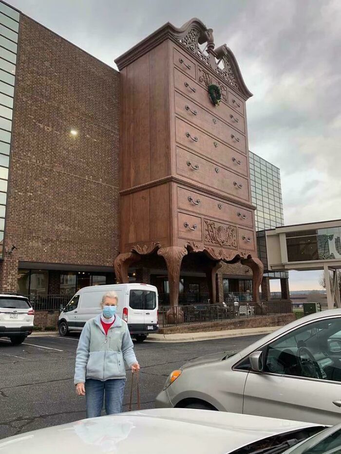 Gigantic wooden dresser sculpture in a parking lot showcasing smart and cool designer creativity.