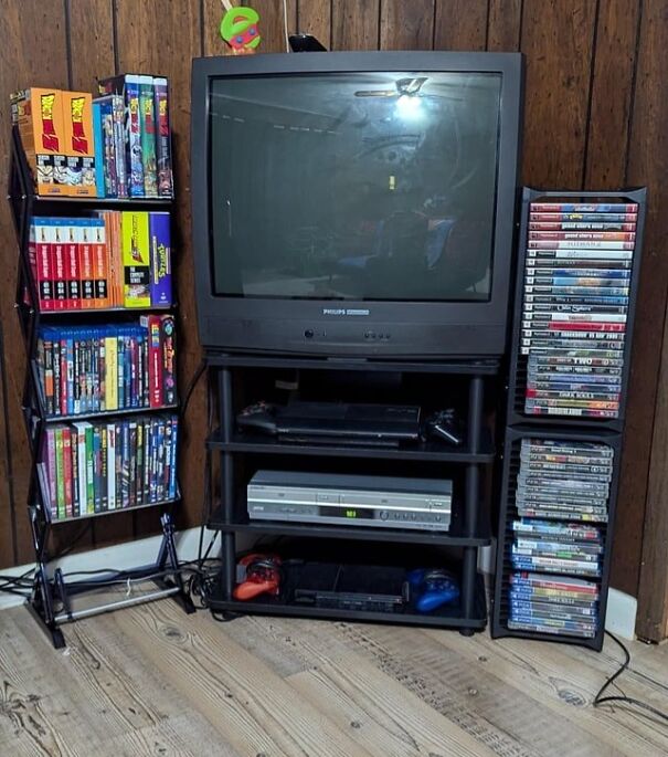Retro finds: old TV, VHS tapes, and DVDs on wooden shelves, evoking nostalgia for the past.