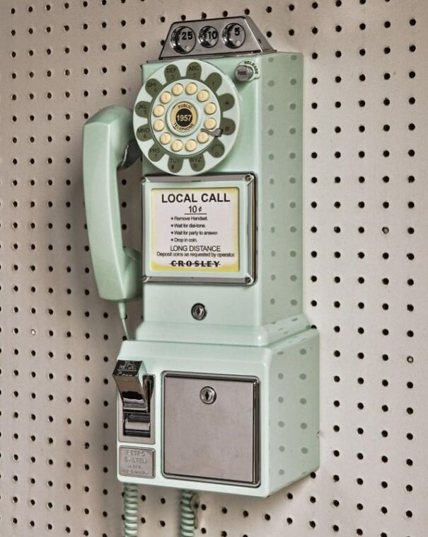 Retro find: Vintage mint green rotary payphone on a perforated board, evoking nostalgia for the good old days.