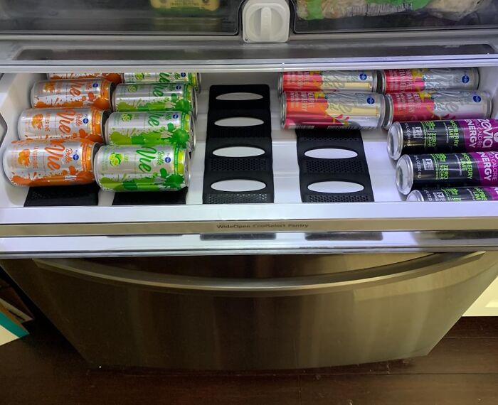 Organized fridge drawer with neatly stacked soda cans, highlighting reinvented pantry storage solutions.