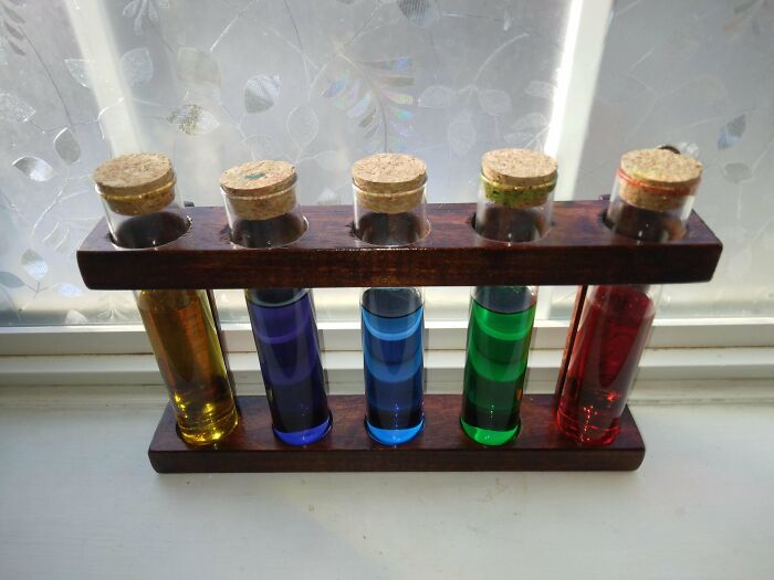 Colorful DIY test tube display with corks on a wooden stand.