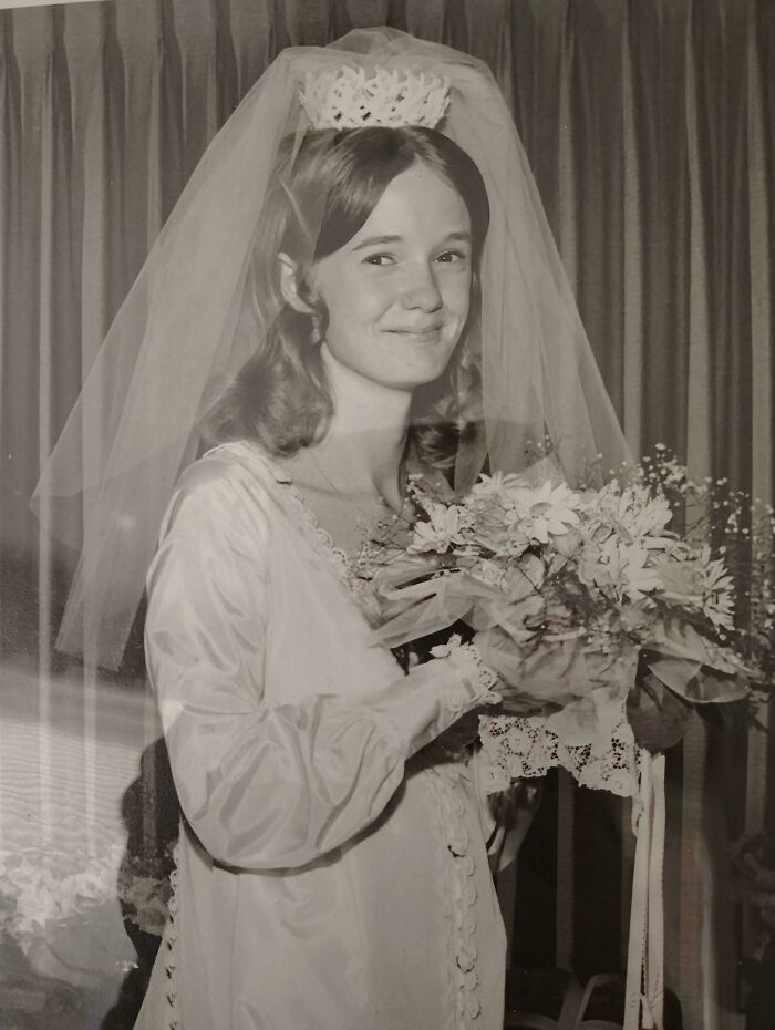 Smiling bride in a vintage wedding dress holding a bouquet, showcasing fascinating old images.