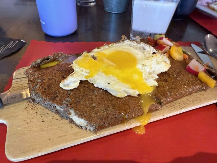 Breakfast served on a wooden board with a fried egg and fruit, one of the most ridiculous ways food is served in restaurants.