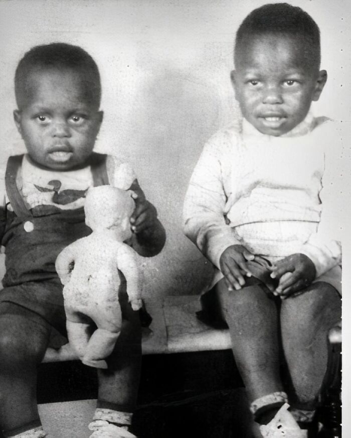 Two young children from the past sitting on a bench, one holding a doll, representing History Cool Kids.