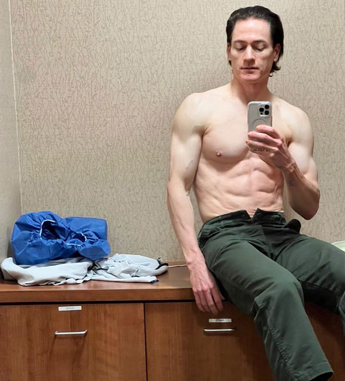 A man taking a mirror selfie, sitting shirtless on a dresser, with a focus on reversing aging. A man taking a mirror selfie, sitting shirtless on a dresser, with a focus on reversing aging.
