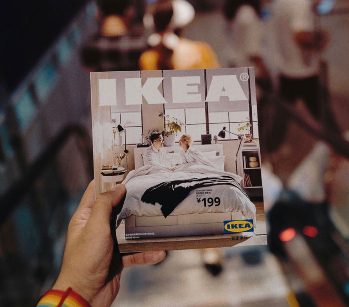 Hand holding an IKEA catalog while descending an escalator, focusing on the cover image. Hand holding an IKEA catalog while descending an escalator, focusing on the cover image.
