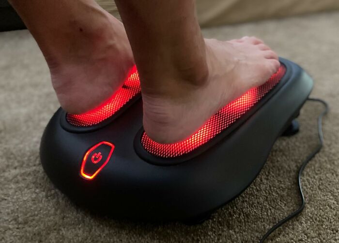 Feet on a lit foot massager, offering relaxation and a reward after a busy day.