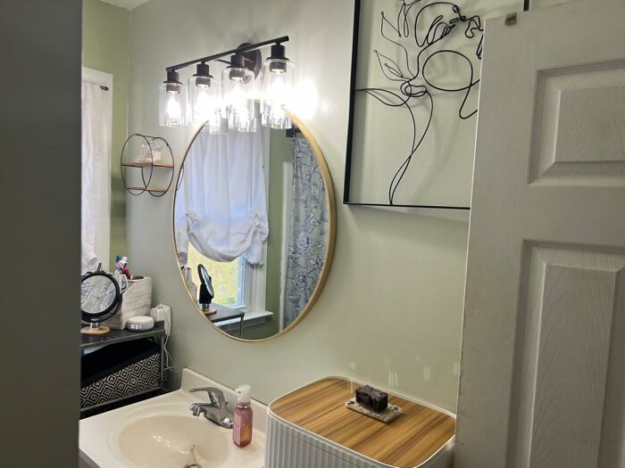 Bathroom interior with round mirror, vanity lighting, and simple decor showcasing low-lift, high-impact improvements.
