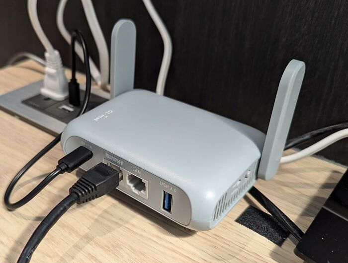 Travel-ready portable router on a desk, connected with cables, ideal for internet access on the go.