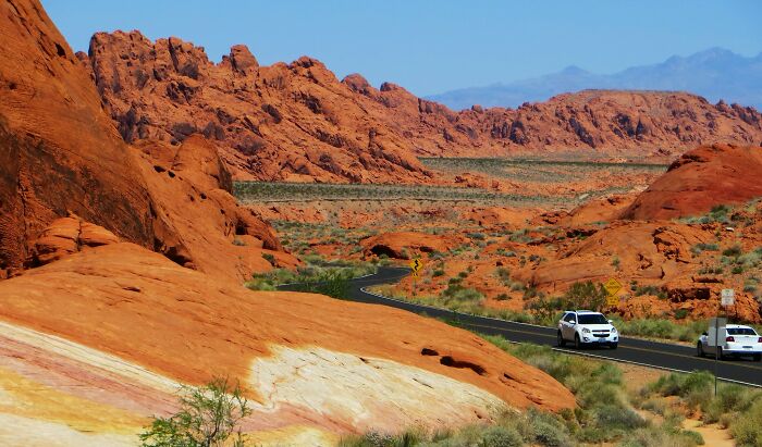 Scenic desert road winding through rocky landscape under clear blue sky, highlighting amazing views states.