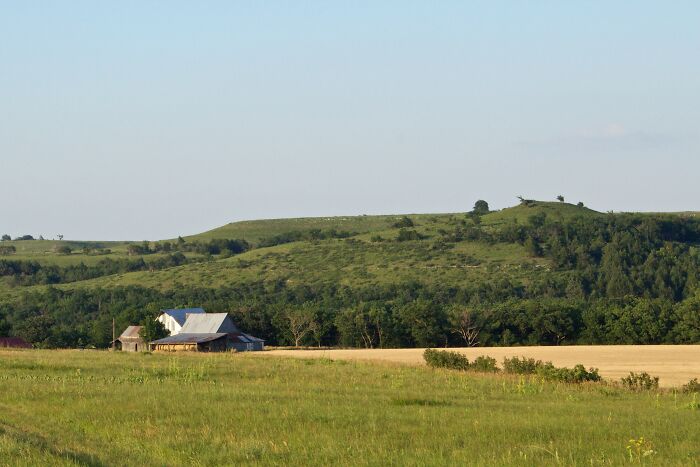 Rural landscape with rolling green hills and a farmhouse, showcasing amazing views in the states.