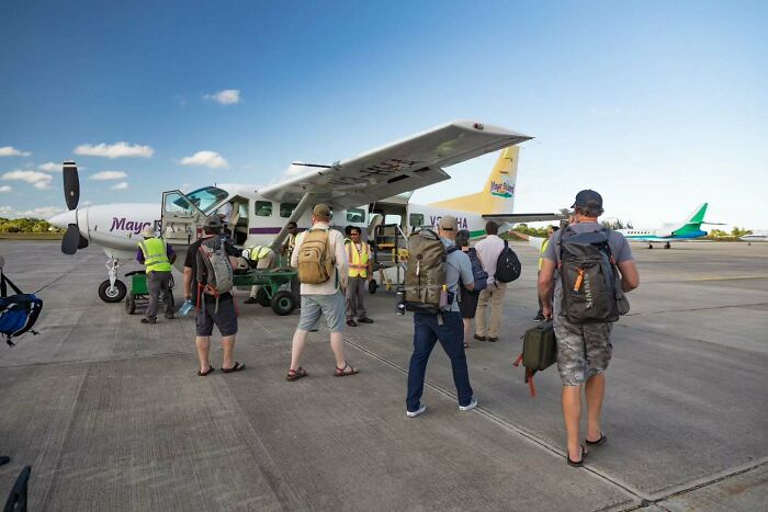 People boarding a small plane at an airport, embarking on a journey to a remote island in Belize. People boarding a small plane at an airport, embarking on a journey to a remote island in Belize.