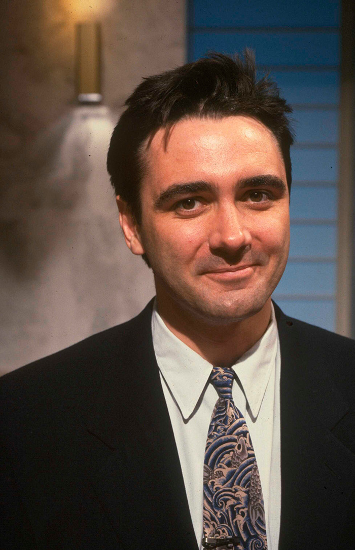 Tony Slattery in a suit and patterned tie smiling warmly. Tony Slattery in a suit and patterned tie smiling warmly.
