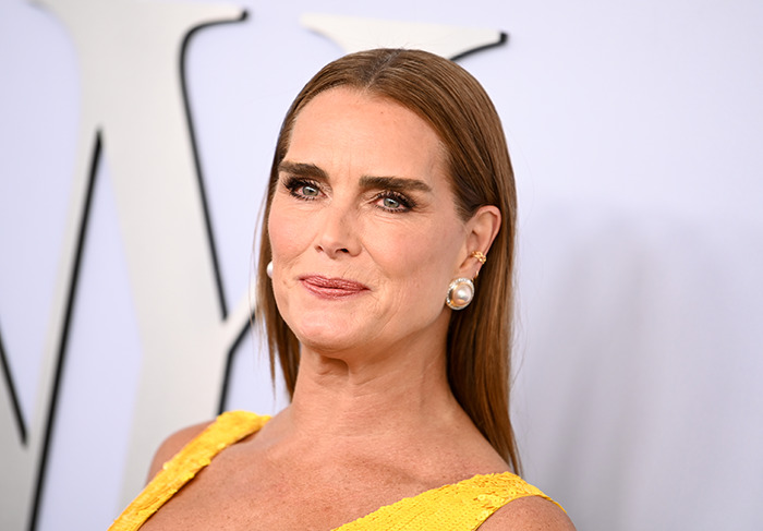 Brooke Shields in a yellow outfit, with pearl earrings, attending a formal event, related to a labia surgery discussion. Brooke Shields in a yellow outfit, with pearl earrings, attending a formal event, related to a labia surgery discussion.