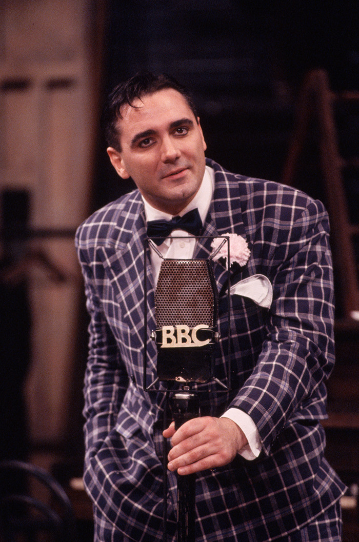 Tony Slattery in plaid suit and bow tie with BBC microphone. Tony Slattery in plaid suit and bow tie with BBC microphone.