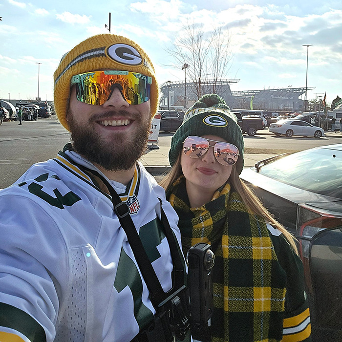 Packers fans in team gear tailgating outside a stadium. Packers fans in team gear tailgating outside a stadium.