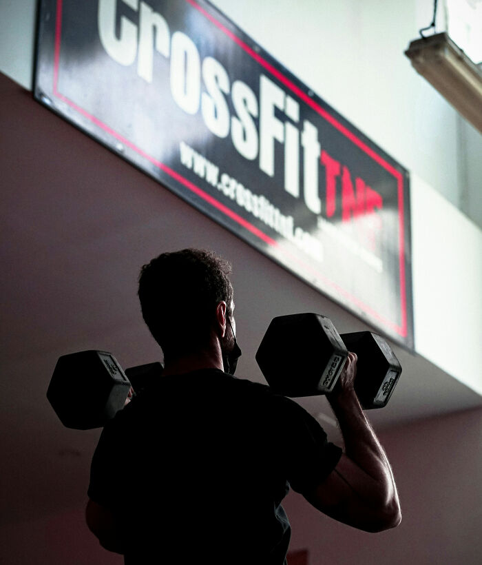 A person lifting dumbbells at a CrossFit gym. A person lifting dumbbells at a CrossFit gym.