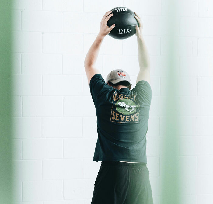 A person lifting a 12-pound medicine ball. A person lifting a 12-pound medicine ball.