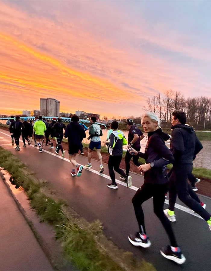 55-year-old woman running marathon with group at sunset, showcasing a world record achievement. 55-year-old woman running marathon with group at sunset, showcasing a world record achievement.
