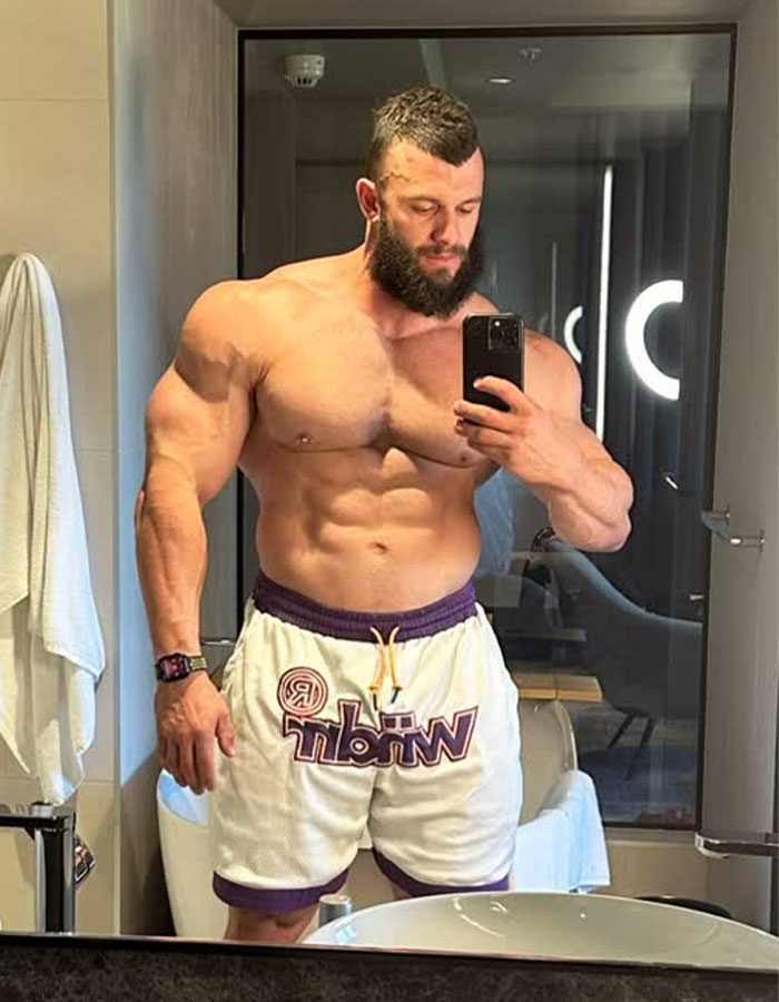 Muscular man in shorts taking a mirror selfie in a well-lit room before an event. Muscular man in shorts taking a mirror selfie in a well-lit room before an event.