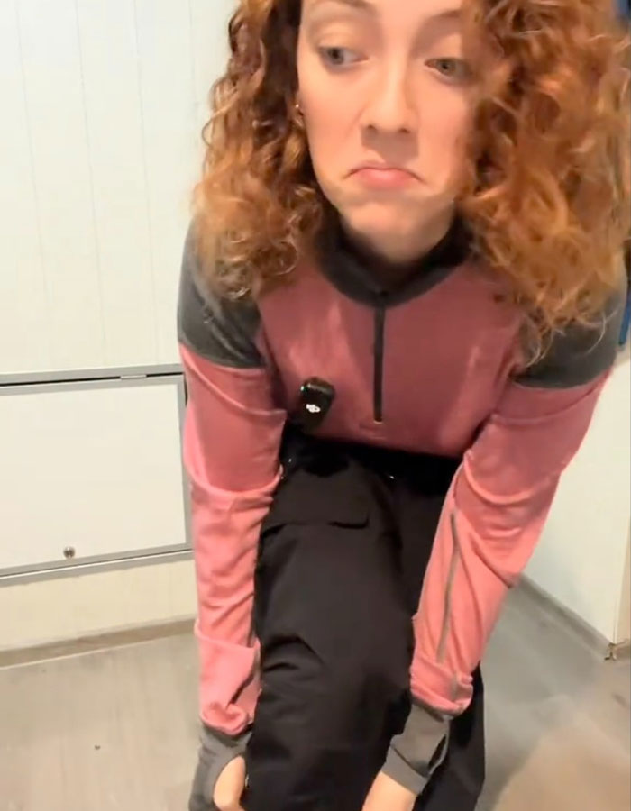 Spanish nurse demonstrates Norwegian clothing secret with a skeptical expression, sparking debate on feeling cold. Spanish nurse demonstrates Norwegian clothing secret with a skeptical expression, sparking debate on feeling cold.