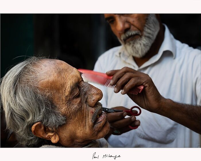 "Paul McKenzie's photo of an elderly man receiving a haircut, showcasing detailed facial features."